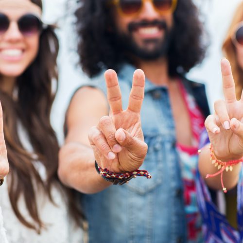 happy young hippie friends showing peace outdoors