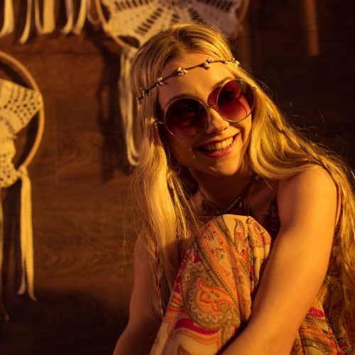 Portrait of young boho styled woman in sunglasses smiling and looking away